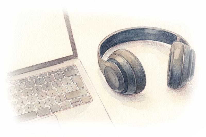black wireless headphones next to the MacBook-