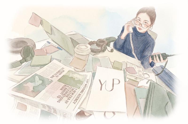 Woman on the phone at a cluttered desk with papers and a laptop